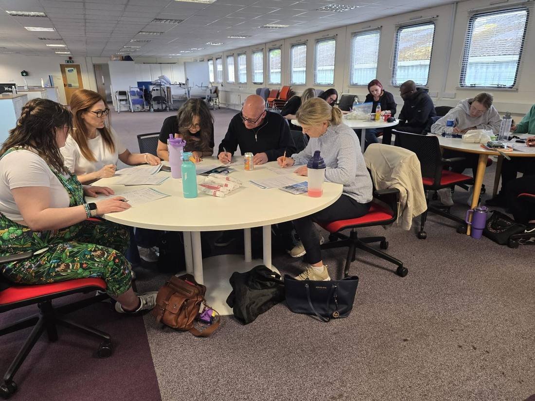 Delegates seated around a table during a first aid theory session at their workplace